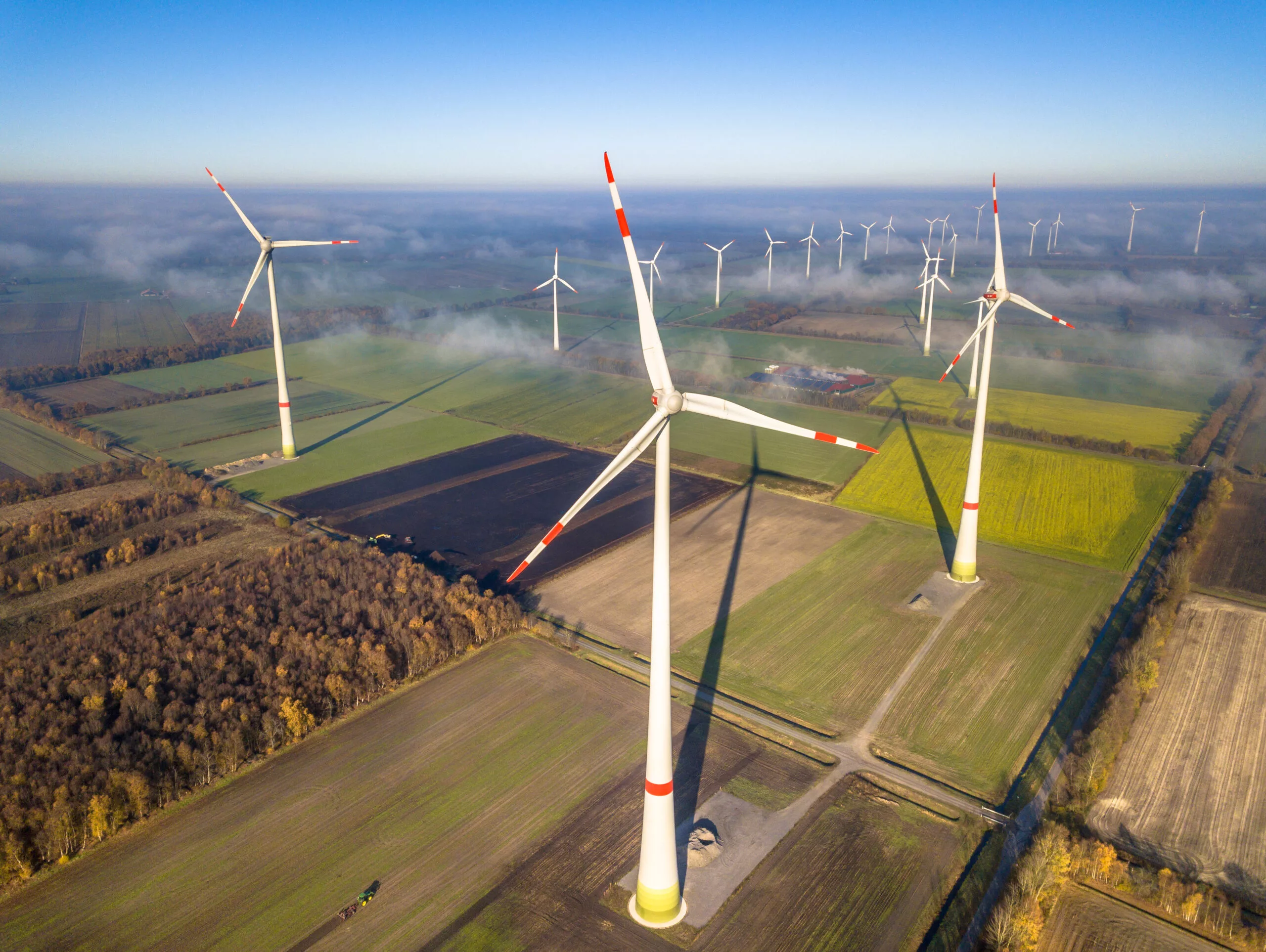 Aerial view of wind energy turbines on windfarm above mist layer on german countryside in the morning sun. Germany