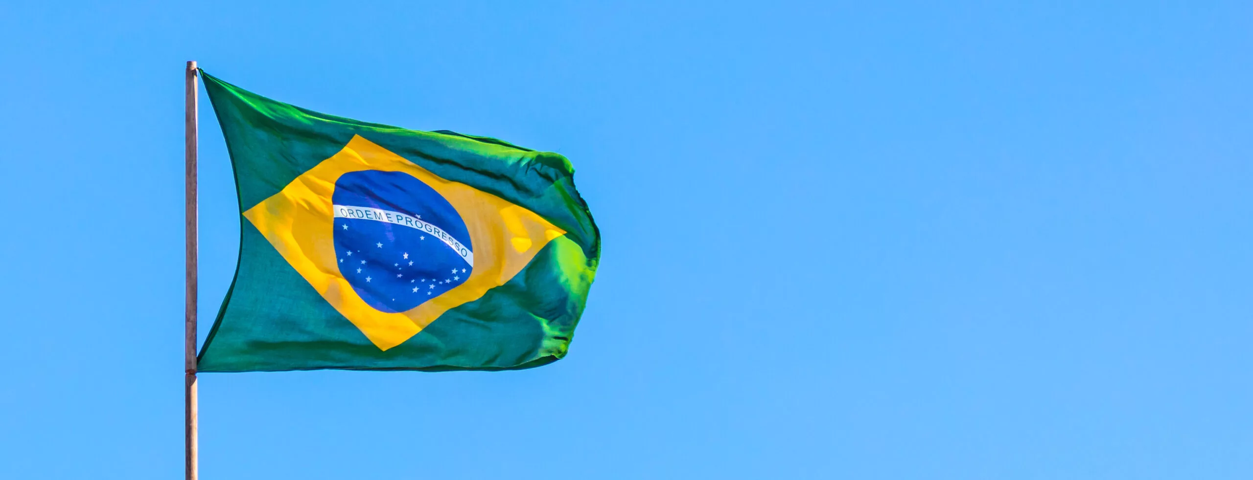 A low angle shot of flag of Brazil on blue sky background